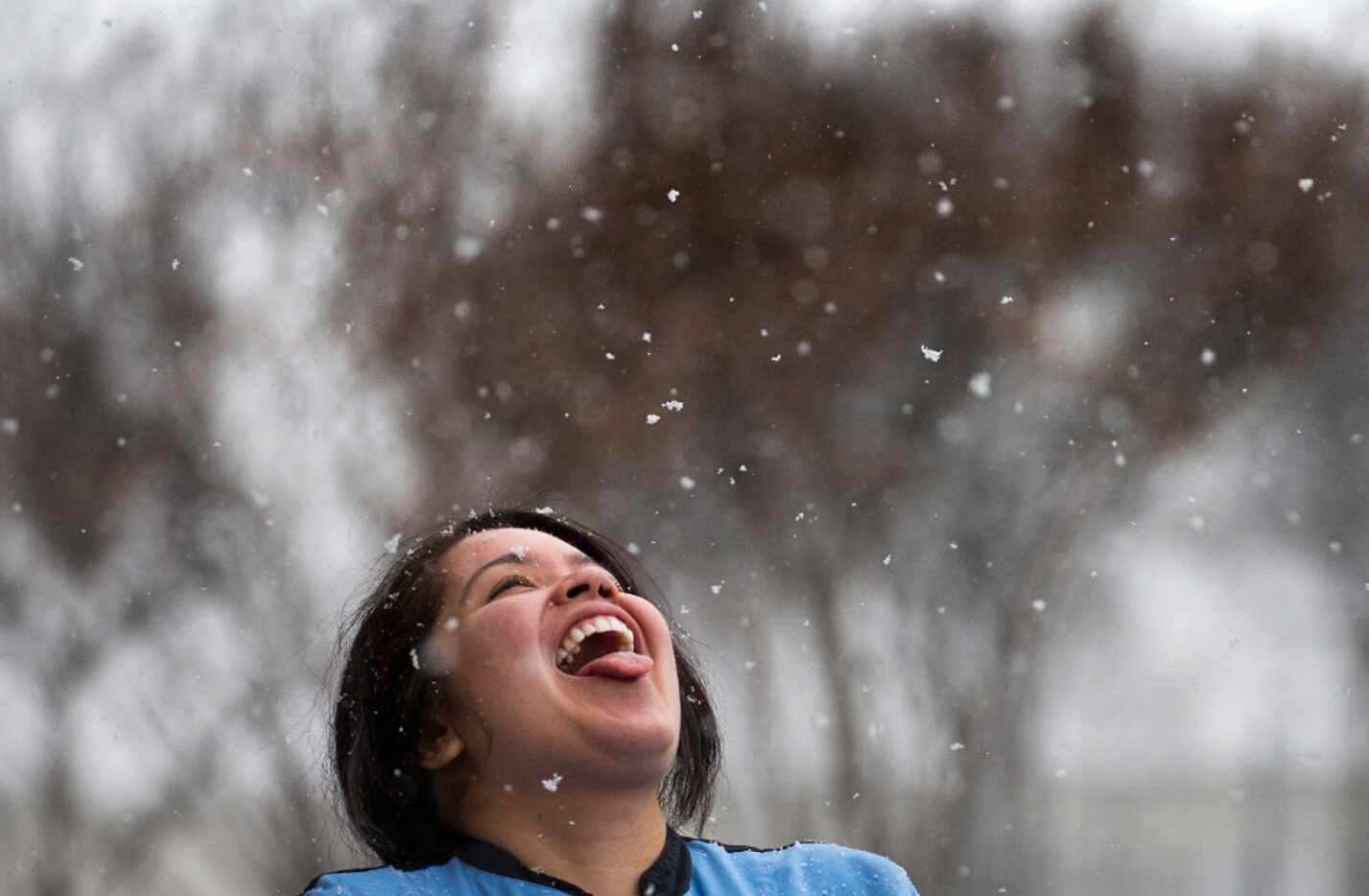 Racene Mendoza steps outside her job at a bakery to try and catch snowflakes as snow falls...