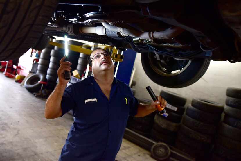 Joaquin Godinez inspects a car for a leak at his auto mechanic shop in southeast Dallas.