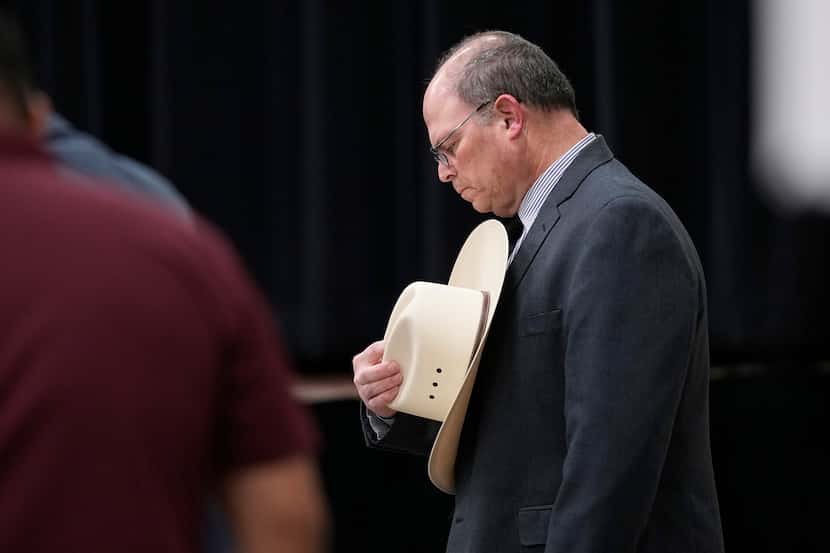 Jesse Prado, an Austin-based investigator, right, bows his head during a prayer before he...