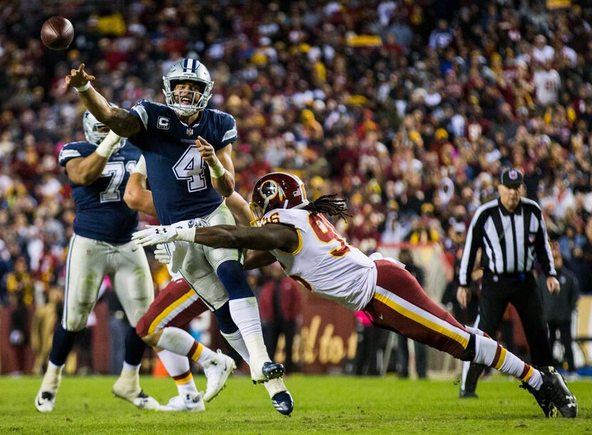 Dallas Cowboys quarterback Dak Prescott (4) throws a pass while being tackled by Washington...