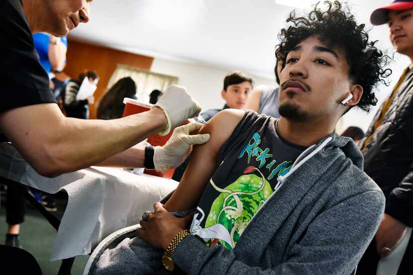 Alan Calvillo, 19, right, receives a flu shot from Medical Doctor Philip Huang, Director of...