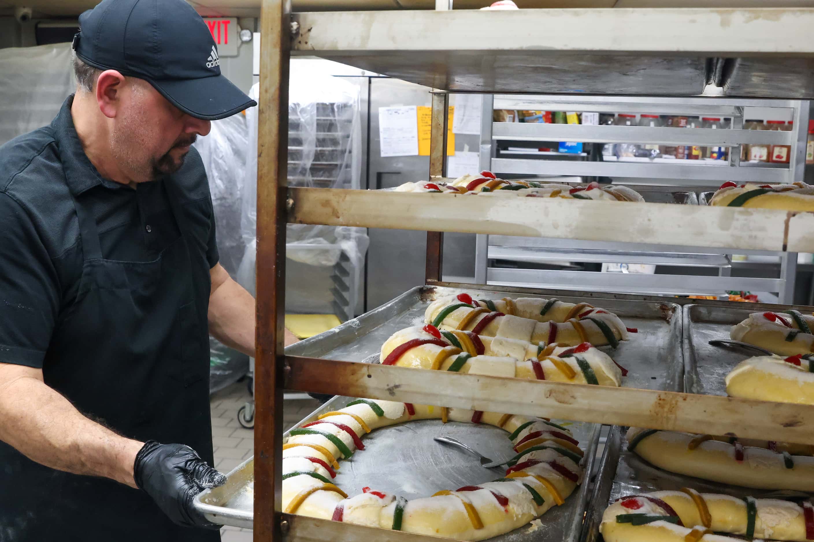 Baker Isaac Ramirez places prepared Rosca de Reyes on racks at Tango Bakery in Garland on...