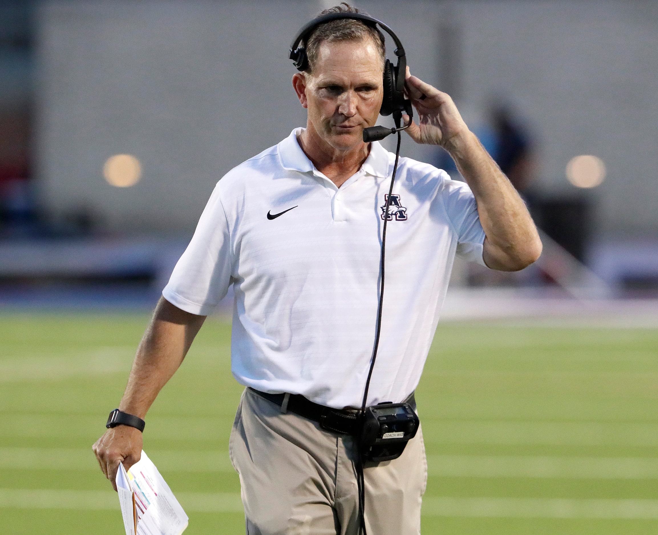 Allen High School head coach Lee Wiginton listens to the headset during the first half as...