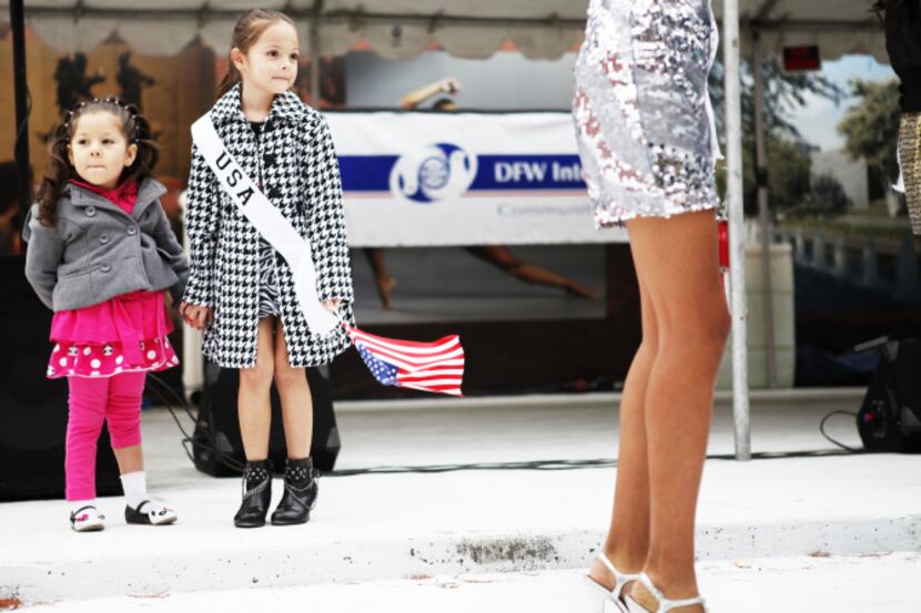 Valeria Hernandez, 4, of Dallas and Emily Fernandez, 6, of Fort Worth watch models onstage...
