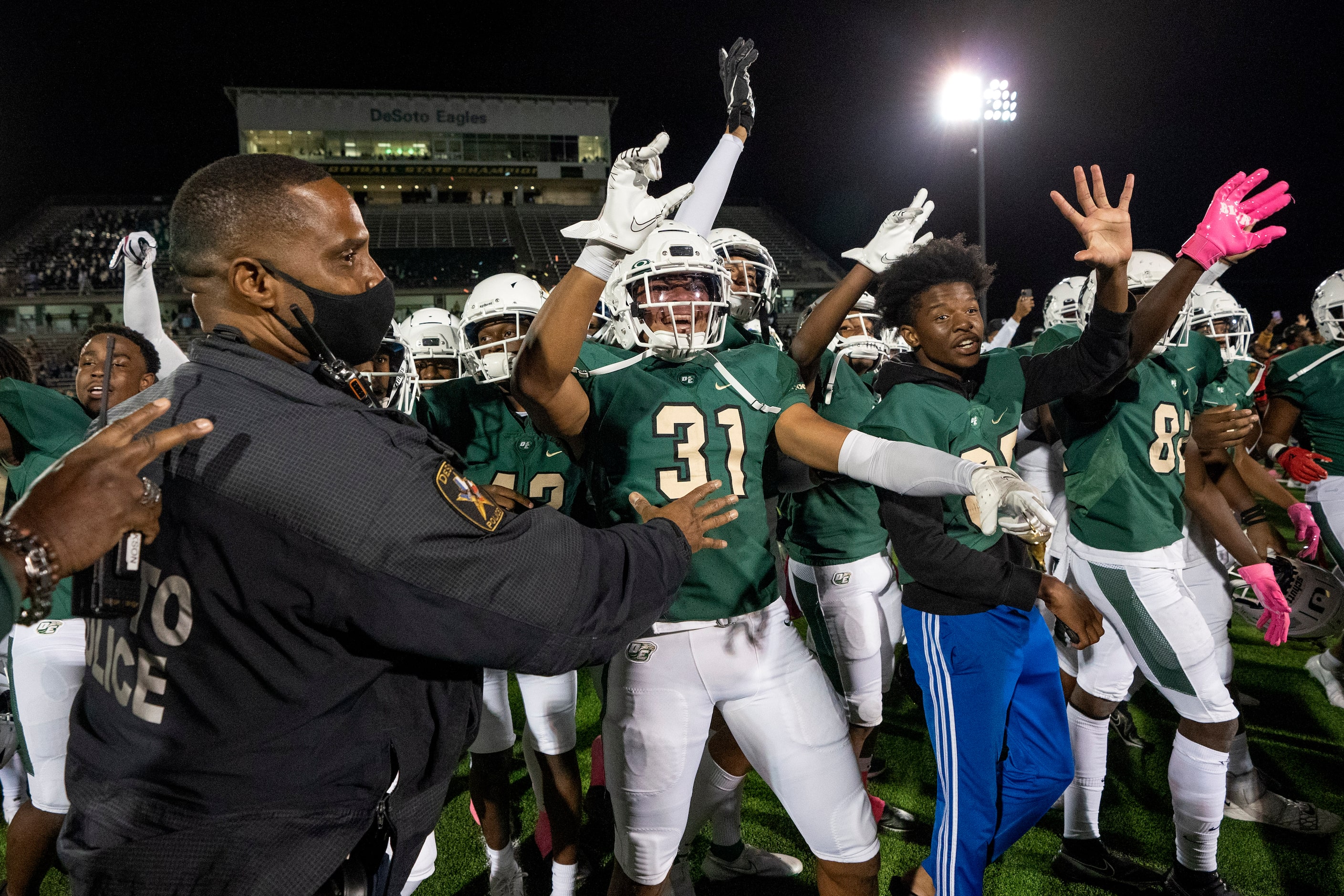 DeSoto police stand guard as DeSoto players wave goodbye to Cedar Hill players at midfield...