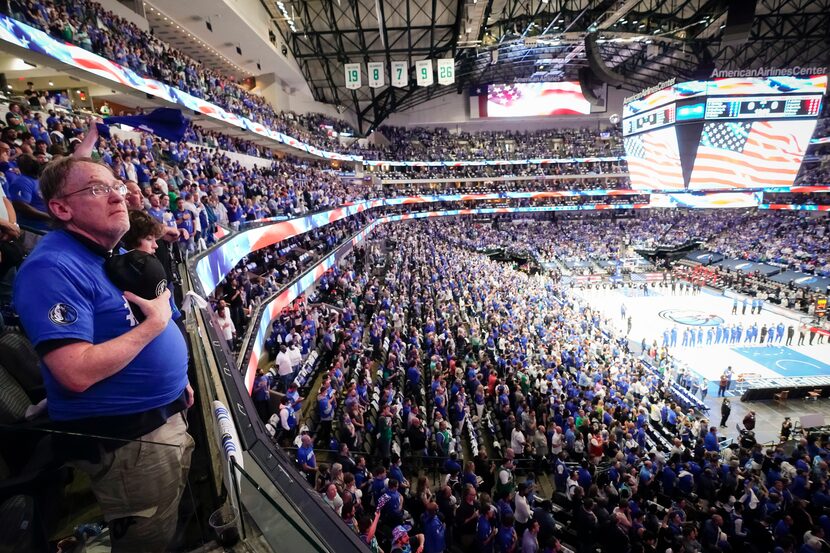 Dallas Mavericks players and fans stand for the national anthem before an NBA playoff...