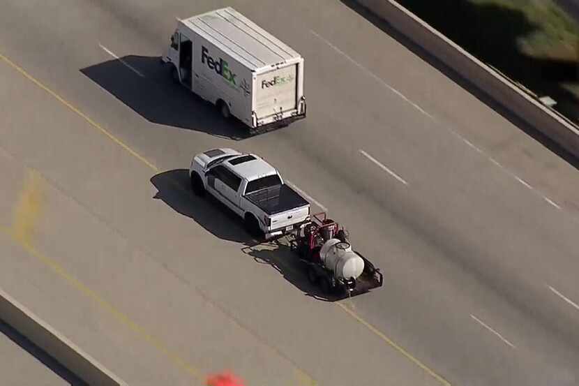 A pickup truck carrying a trailer with a tanker attached makes its way into western Dallas...