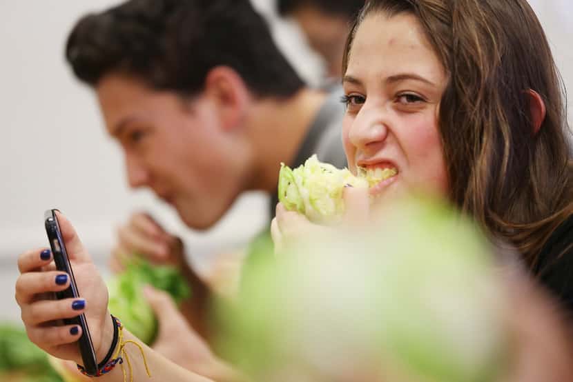 Senior Cammy Rodriguez bites into a head of lettuce during a meeting of The Lettuce Club at...