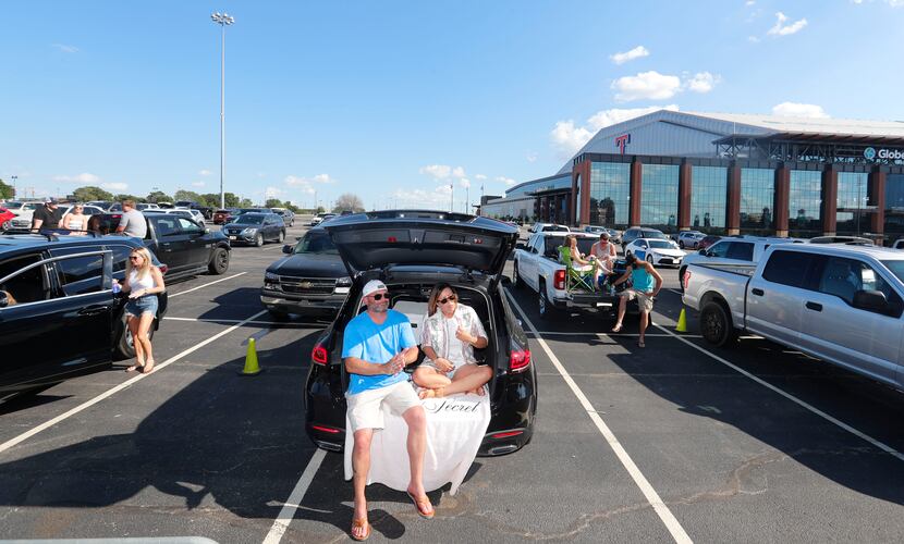 Husband and wife Brad and Lisa Catlett sit in the back of their vehicle parked with social...