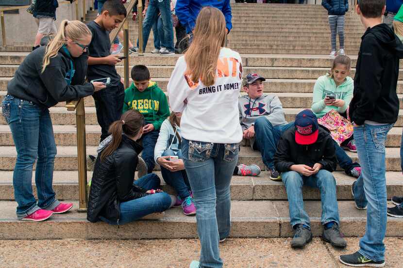 A group of teens check their smartphones outside the Natural History Museum in Washington.