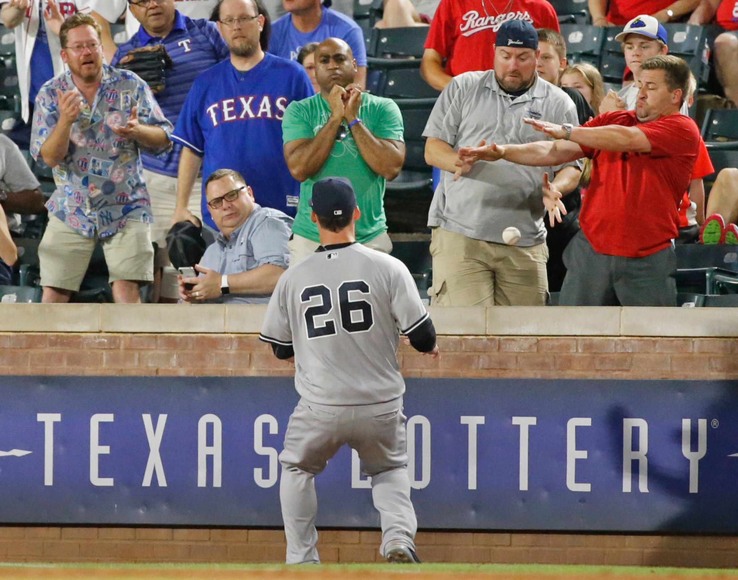 Baseball fans try to catch a foul pop by Robinson Chirinos in the ninth inning along the...