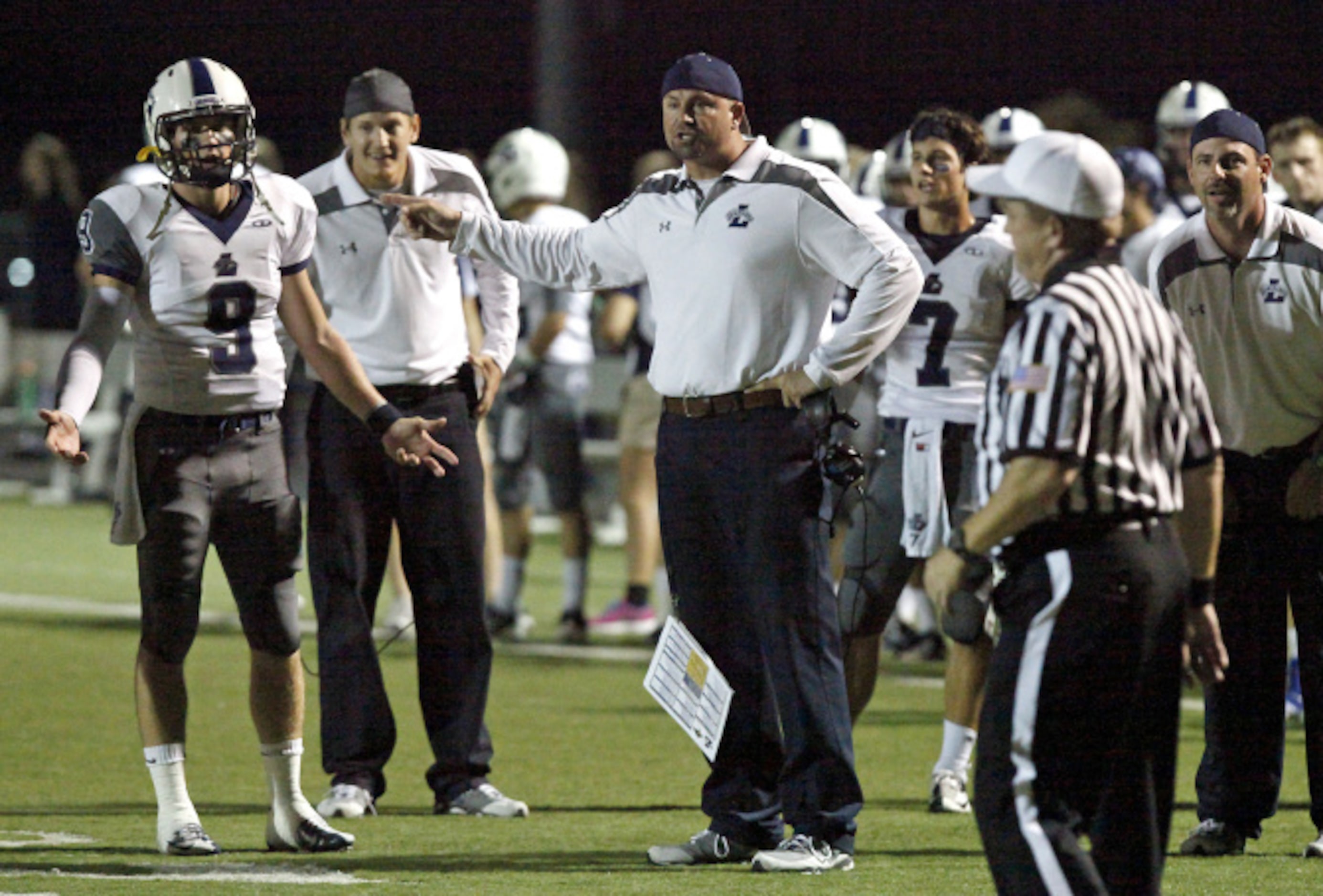 Liberty High School quarterback Foster Ford (9) and head coach Greg Price (center) quize the...