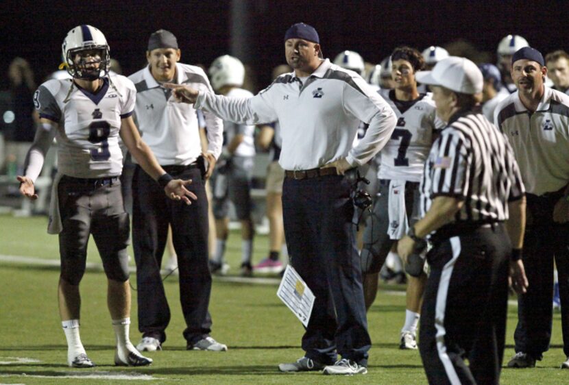 Liberty High School quarterback Foster Ford (9) and head coach Greg Price (center) quize the...