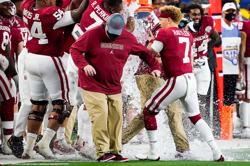 Oklahoma quarterback Spencer Rattler (7) holds onto head coach Lincoln Riley as he is doused...