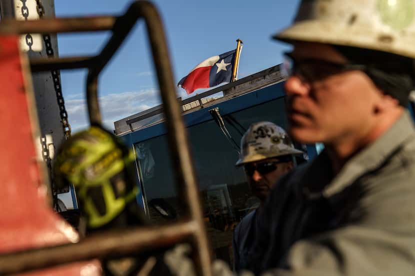 The Texas flag flies above workers at Latshaw oil drilling rig #43 in the Permian Basin in...
