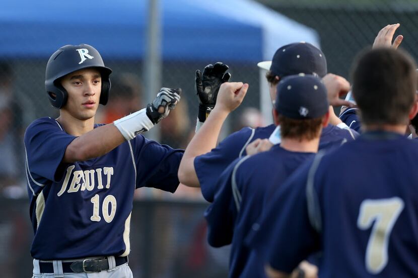 Jesuit Rangers center fielder Darius Hill (10) is met at the bench after scoring against the...