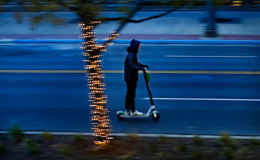 A bundled scooter rider breezes down Main St. in downtown Dallas as temperatures continue to...