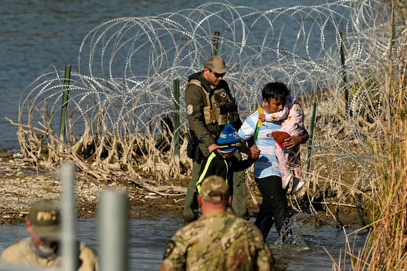 Migrants are taken into custody by officials at the Texas-Mexico border, Wednesday, Jan. 3,...