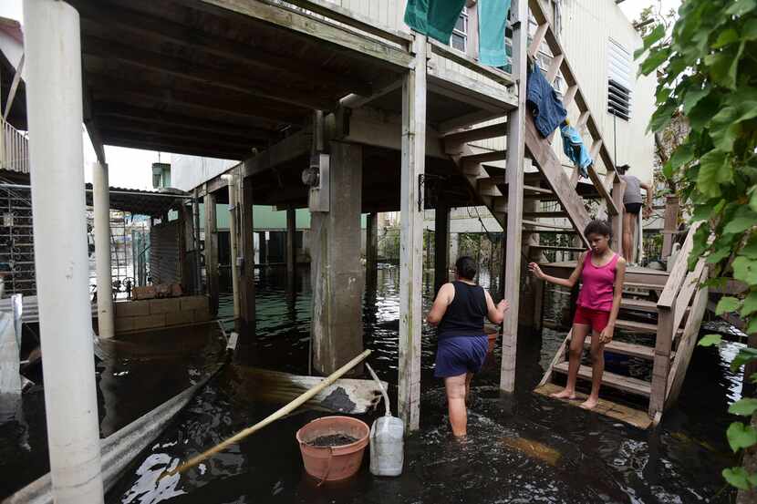 Juana Matos residents walk through a flooded area caused by the passage of Hurricane Maria,...