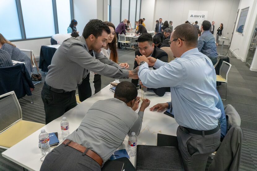 A group of Merit America participants wearing business casual clothing participate in a...