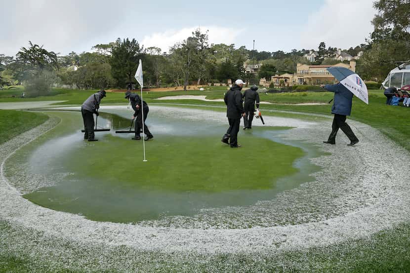A rules official directs greenskeepers trying to clear hail and standing water from the...
