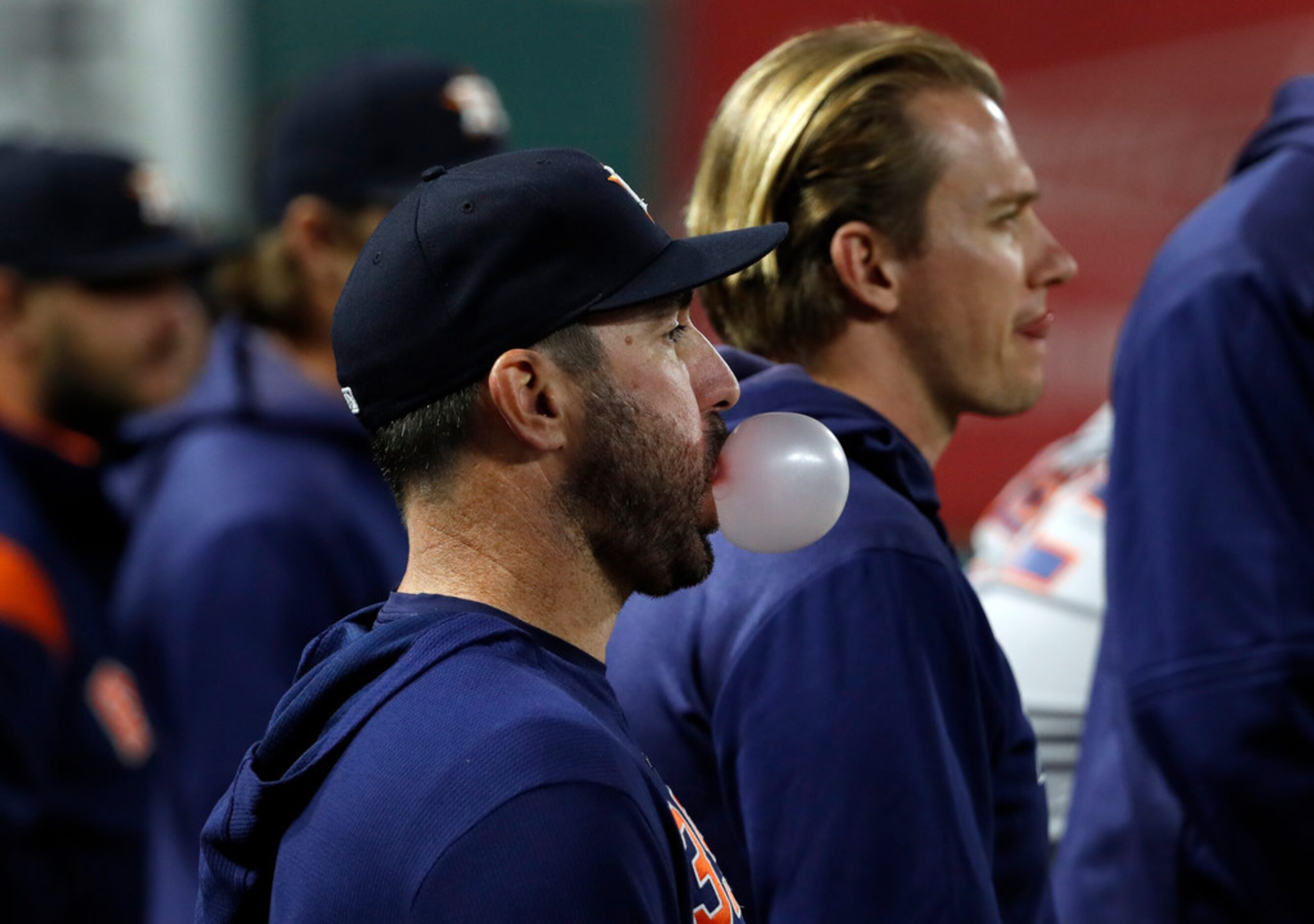 Houston Astros' Justin Verlander blows a bubble as he stands in the dugout watching play...