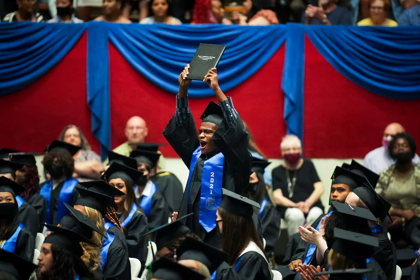 Graduate Kadar Price raises his diploma in celebration during commencement ceremonies for...