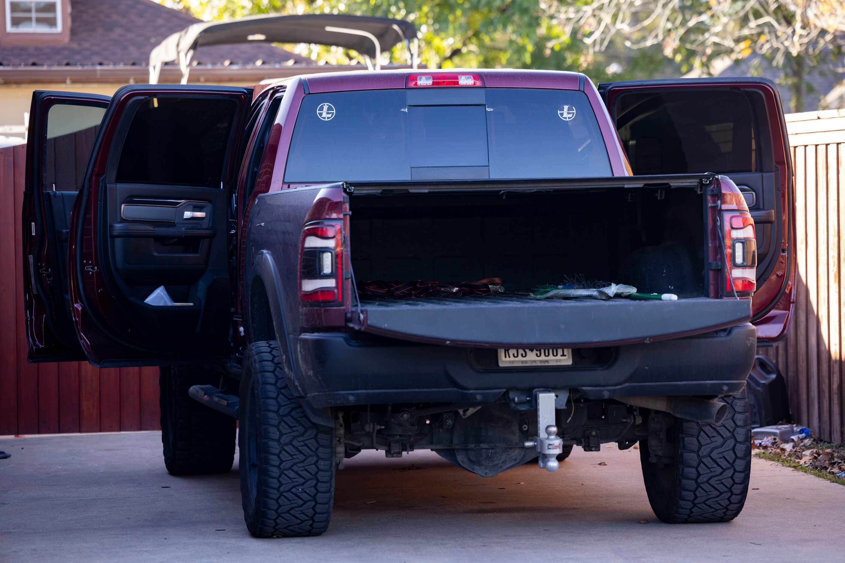 A pickup truck with the doors open sits in the driveway of the home where four people,...