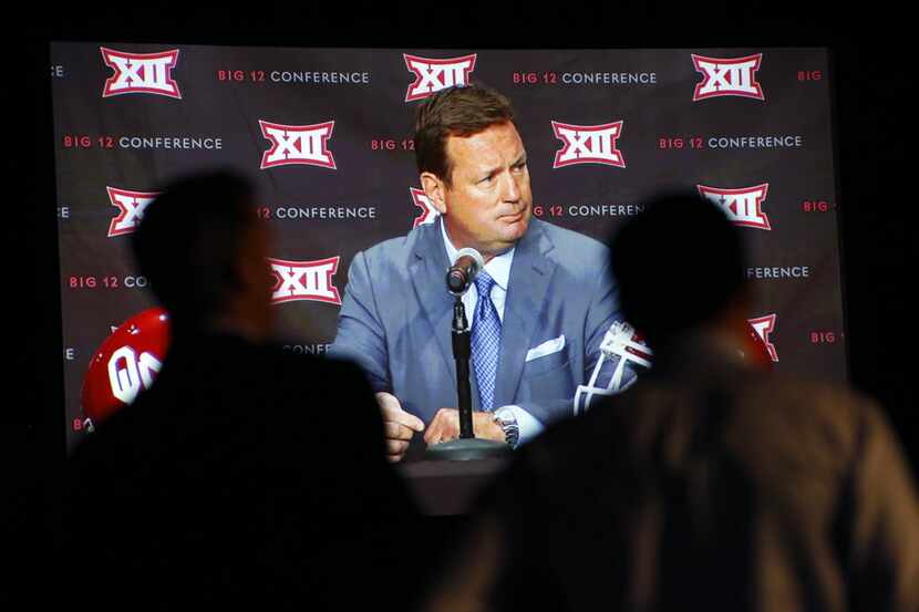 Reporters watch Oklahoma head football coach Bob Stoops respond to questions on the video...