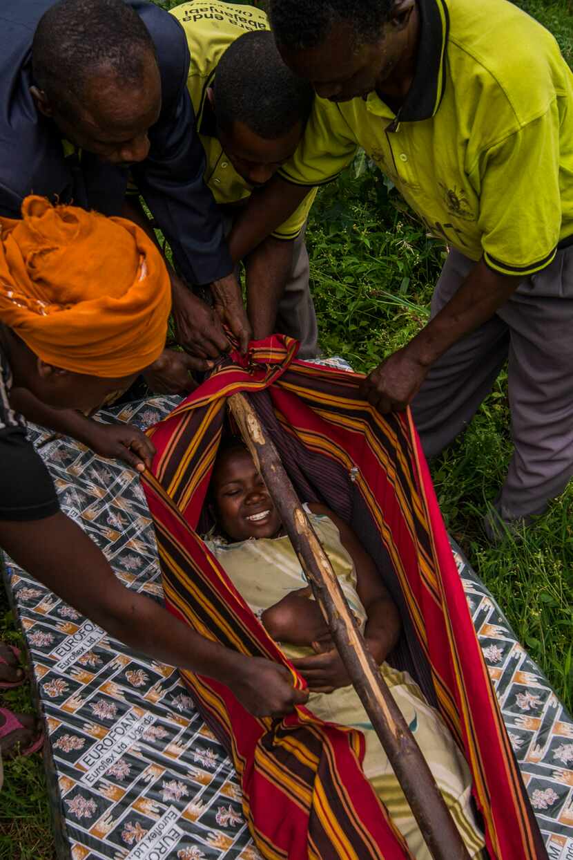 In this case in June 2014, villagers prepare to carry a woman in labor from her village to a...