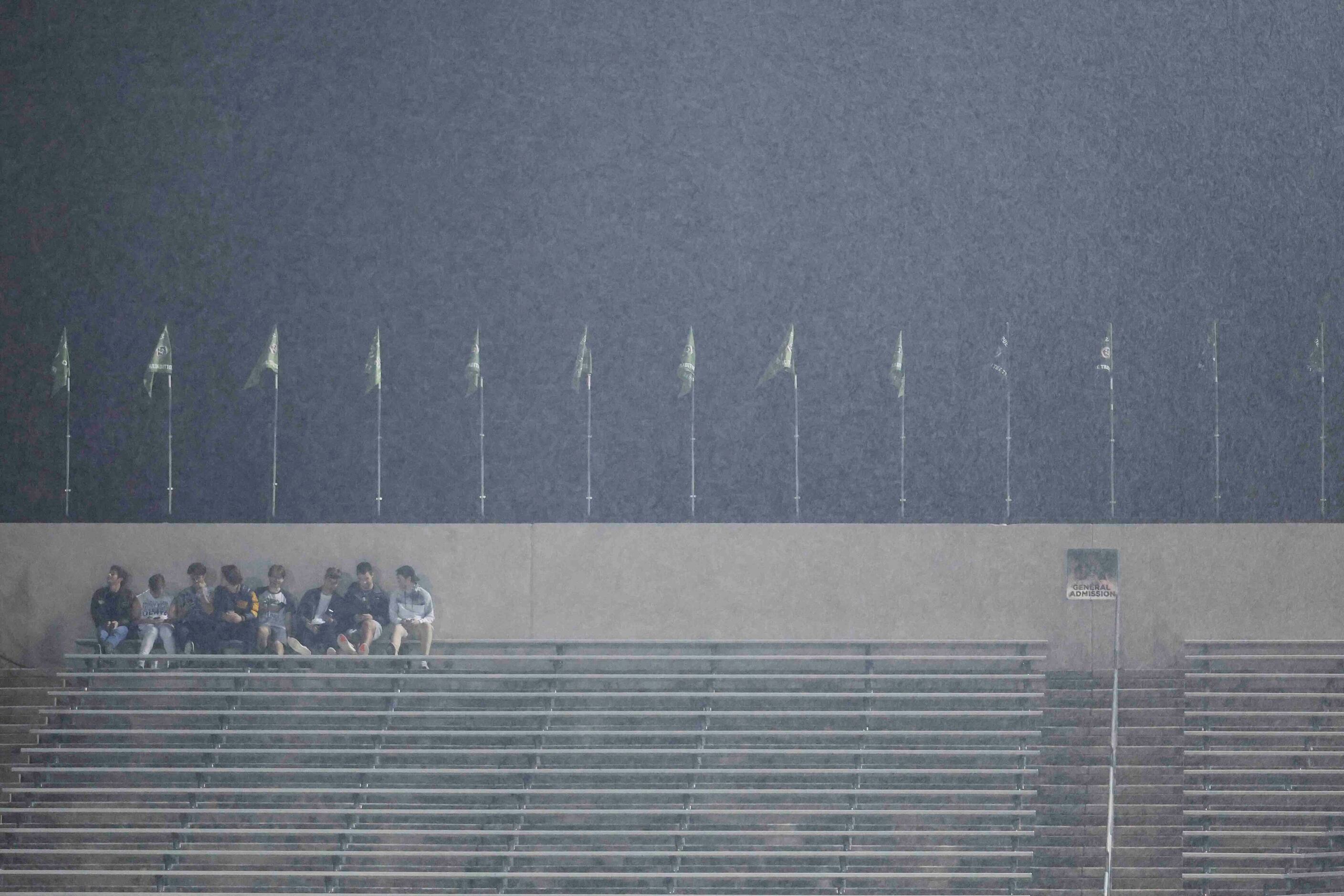 Rain pours as some students watch the second half of a football game between Grapevine and...