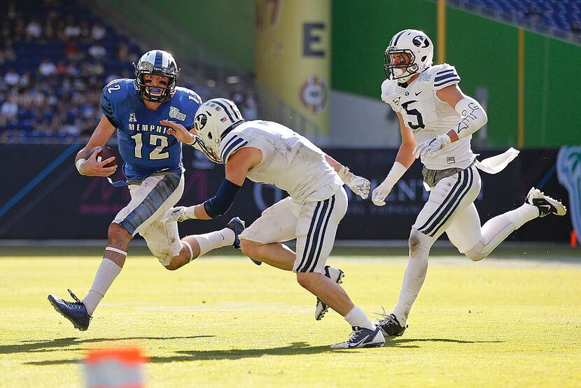 MIAMI, FL - DECEMBER 22: Paxton Lynch #12 of the Memphis Tigers carries as Skye PoVey #7 and...
