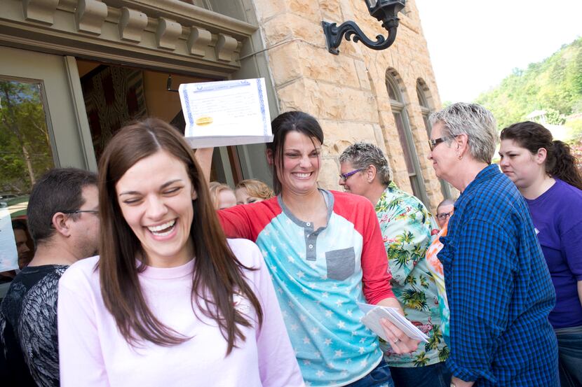 Kristin Seaton, center, of Jacksonville, Ark., holds up her marriage license as she leaves...