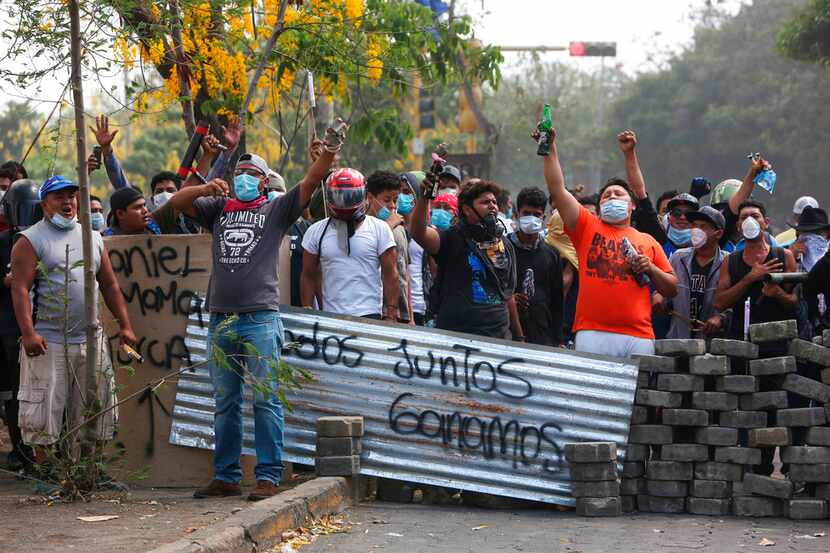Un grupo de manifestantes lanza consignas tras bloquear una calle en un confrontamiento con...