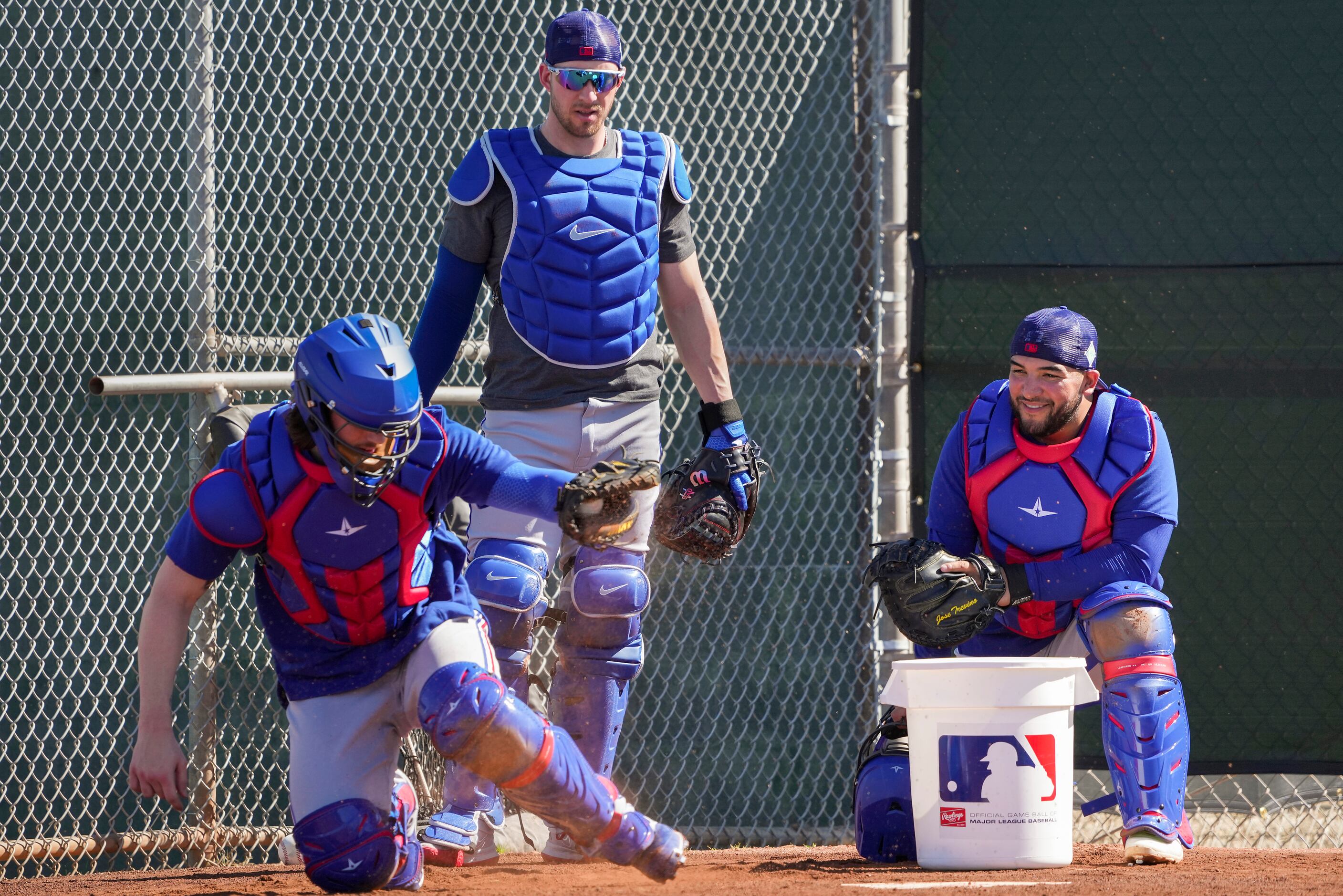 Texas Rangers catchers Jose Trevino (right) and Mitch Garver (standing) watch as catcher...