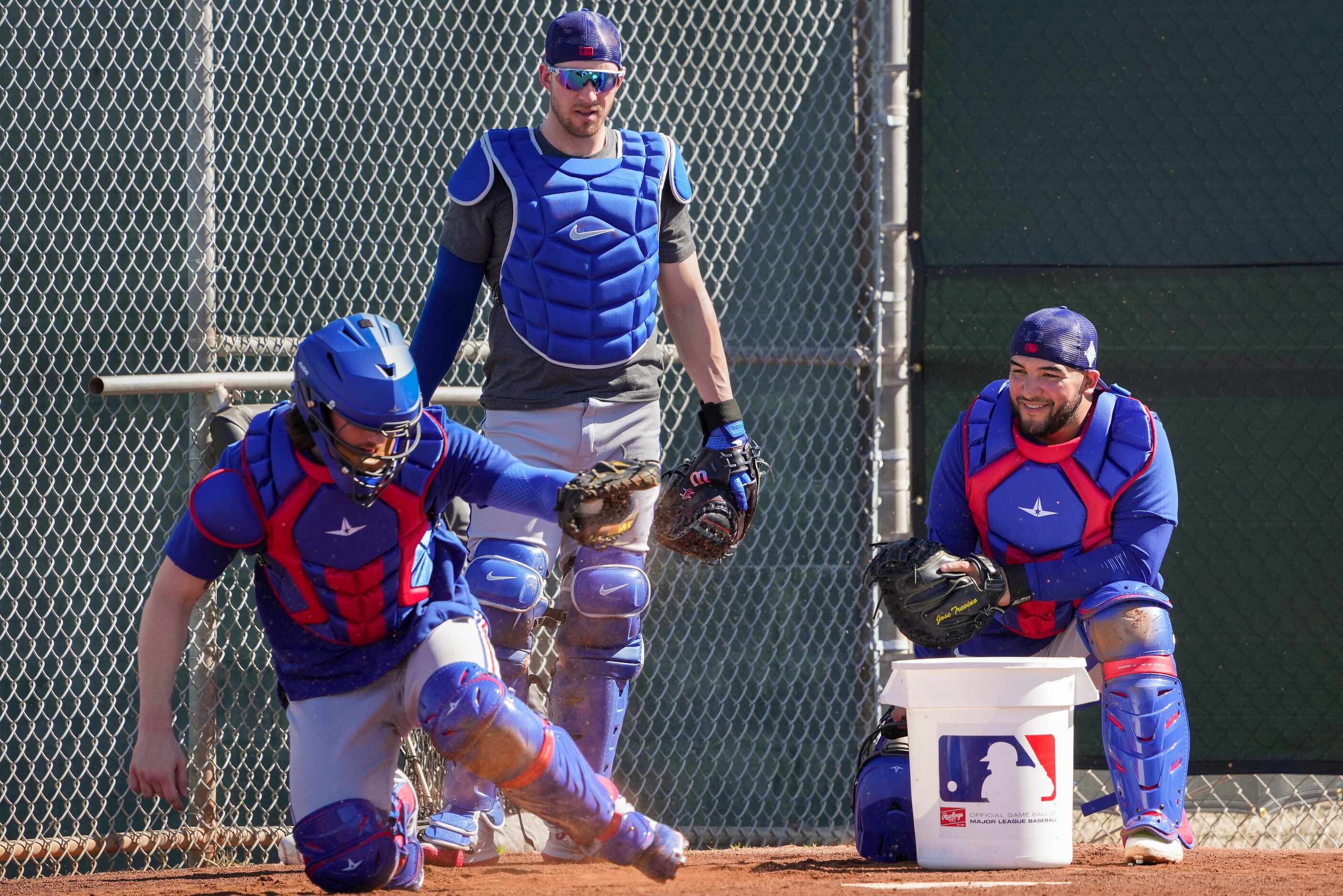 Texas Rangers catchers Jose Trevino (right) and Mitch Garver (standing) watch as catcher...