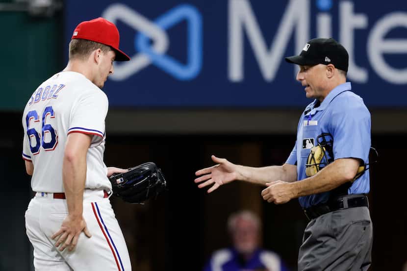 Home plate umpire Dan Iassogna inspects Texas Rangers relief pitcher Josh Sborz’s glove...
