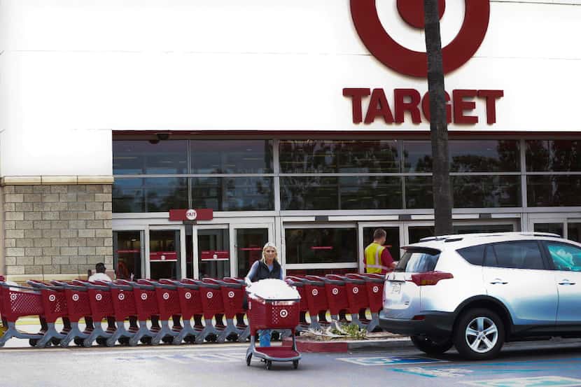 In this Thursday, May 26, 2016, photo, a woman pushes her shopping cart as an employee pulls...