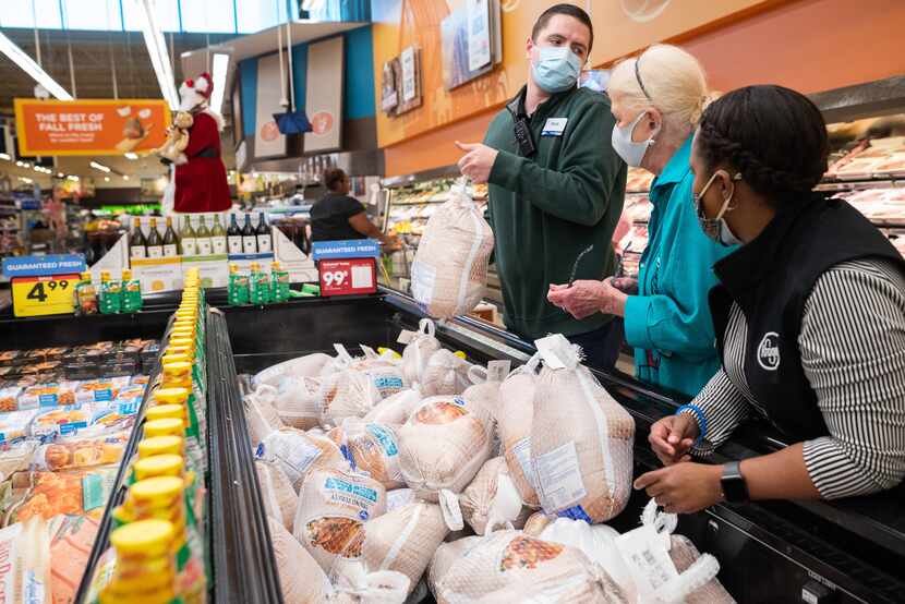 Kroger store manager Matt Cotter lifts a frozen turkey for shopper Shelley O'Connor, 79, as...