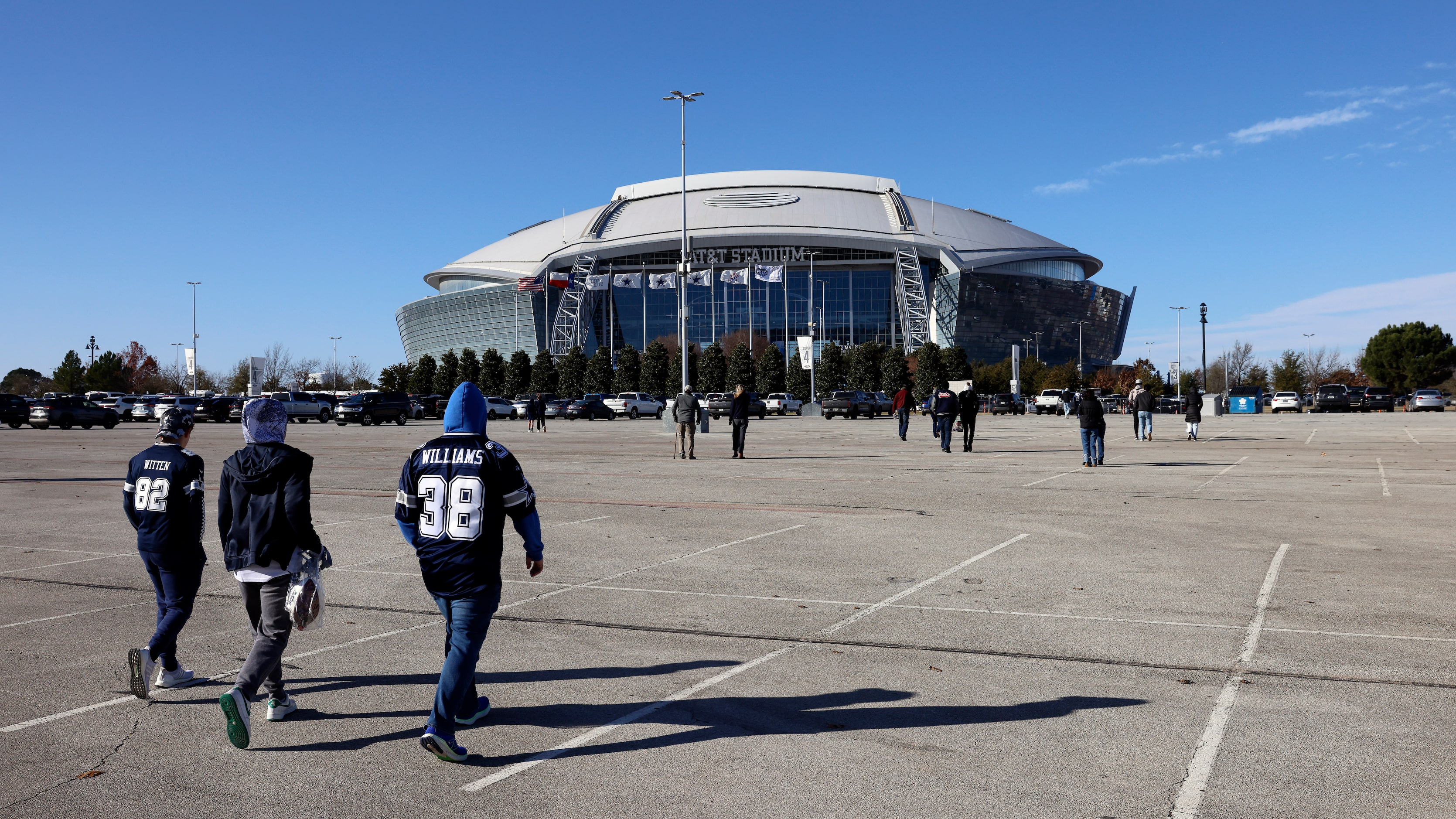 Dallas Cowboys fans walk across a nearly empty parking lot as cold winds howled outside of...