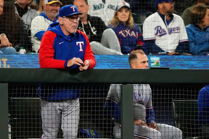 Texas Rangers manager Bruce Bochy, left, watches with Nathaniel Lowe from the dugout during...