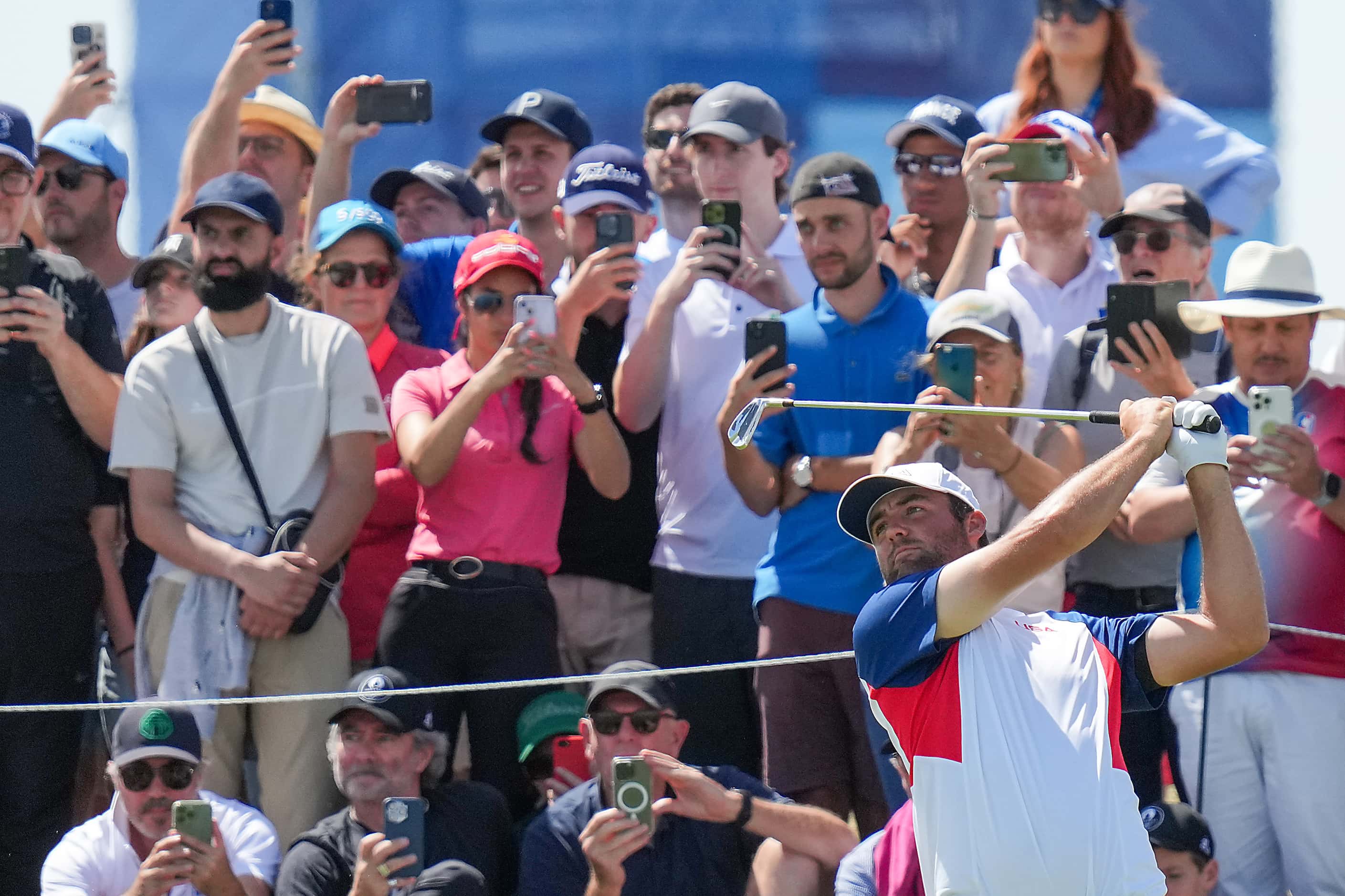 Spectators train their camera on Scottie Scheffler of the United States as hits from the...