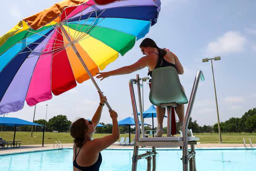 Emily Buss, 16, reaches for an umbrella to put on the lifeguard stand June 9 at the Allen...