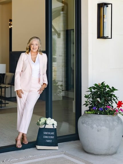 Woman leaning on glass doorway in a pink suit