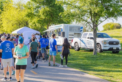 Participants in a 5K race event gather in front of the Comerica Community Engine truck and...