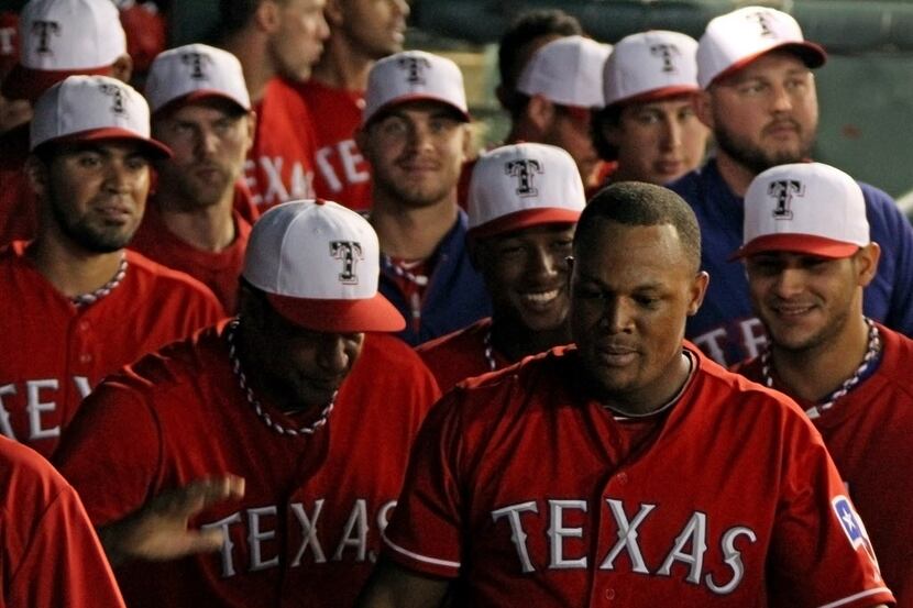 Teammates gather around Texas third baseman Adrian Beltre in the dugout after he hit the...
