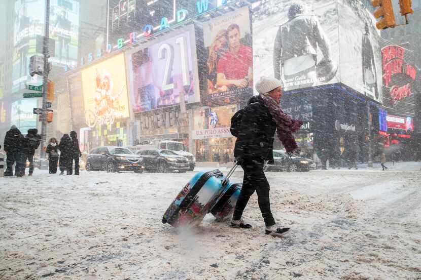 NEW YORK, NY: Rebecca Hollis of New Zealand drags her suitcases in a snowstorm through Times...
