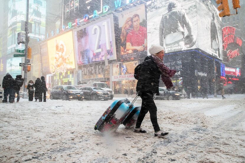 NEW YORK, NY: Rebecca Hollis of New Zealand drags her suitcases in a snowstorm through Times...