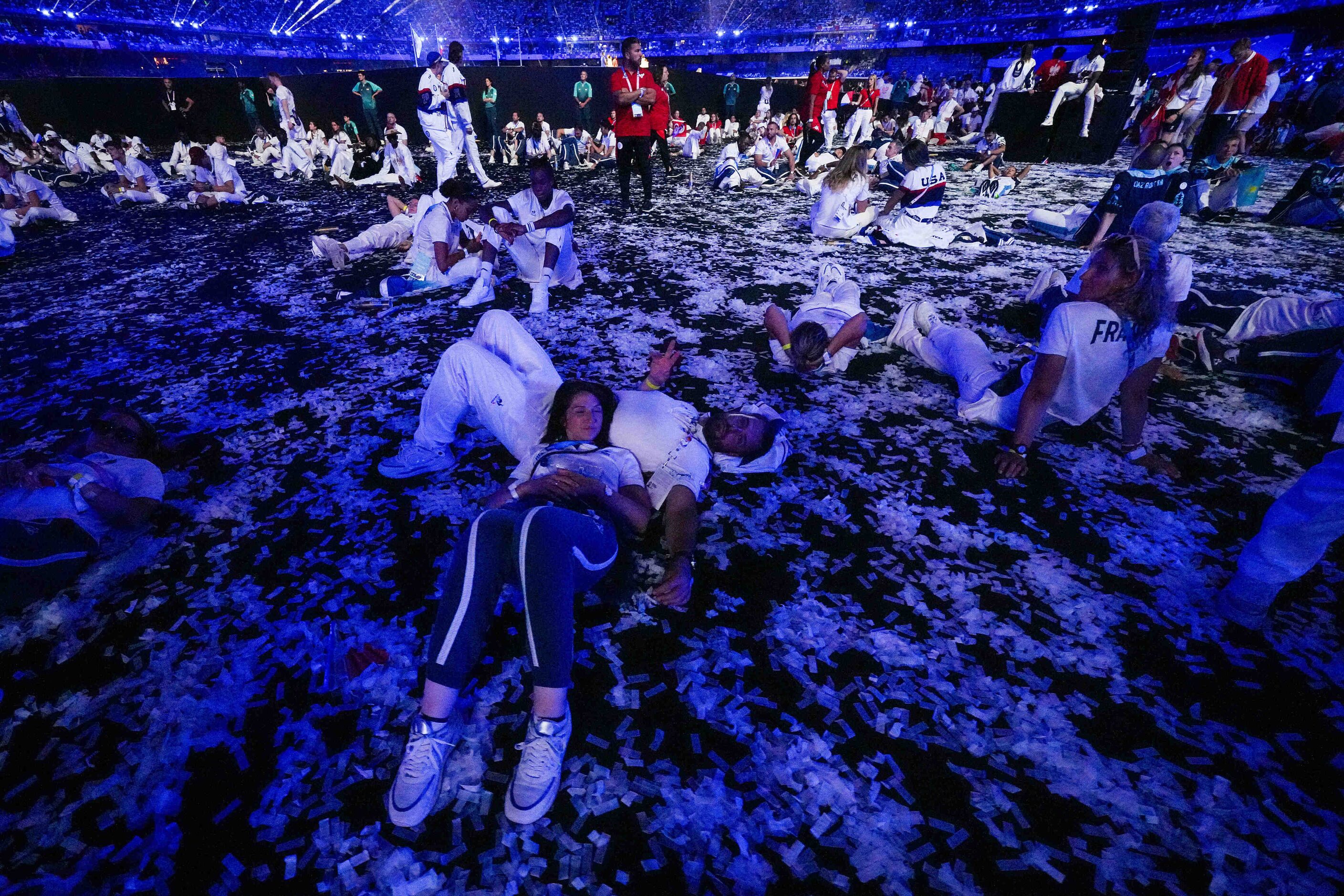 French athletes relax on the ground during closing ceremonies for the 2024 Summer Olympics...