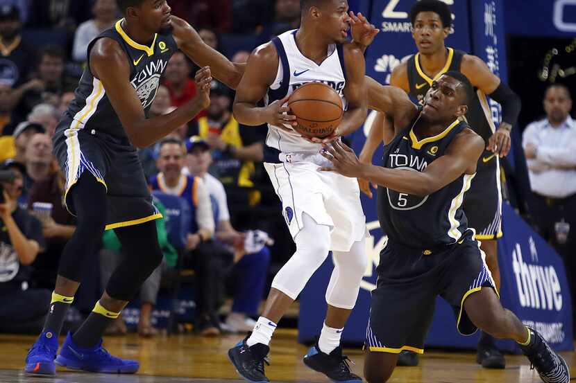 Golden State Warriors' Kevin Durant, left, and Kevon Looney (5) guard Dallas Mavericks'...